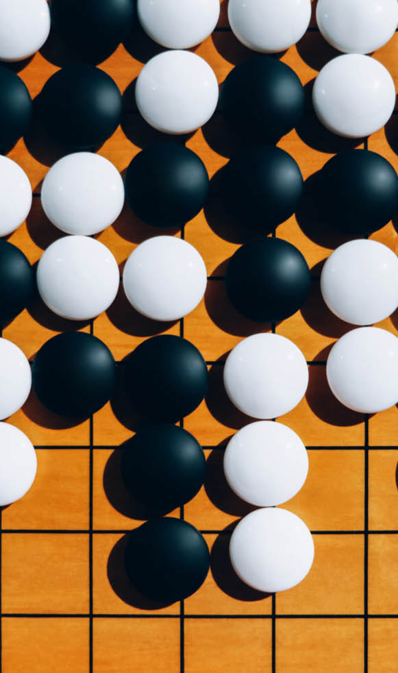 Close-up wooden board for playing go with black and white stones on shadow