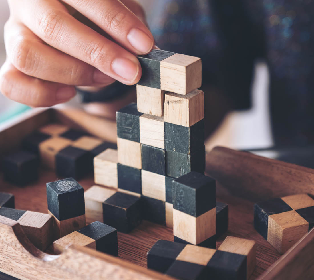 Closeup image of people playing and building wooden puzzle game